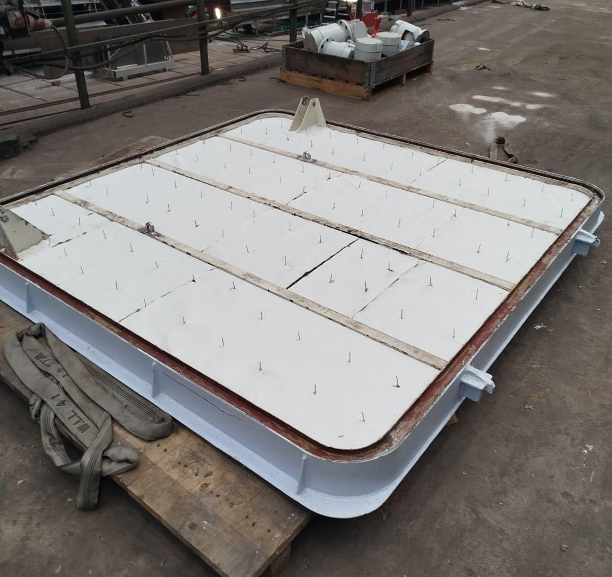 Insulated hatch cover on a trestle at a shipyard, the outer skin fastened with pins